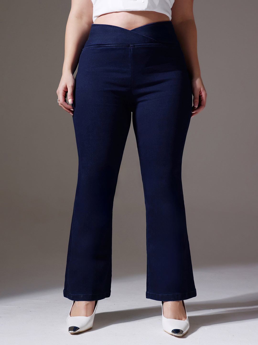 Mid-sized woman wearing a pair of Bootcut High-Rise Navy Blue Denim Jeans which provides light tummy smoothening with the patented CHASEshapeTM Panel