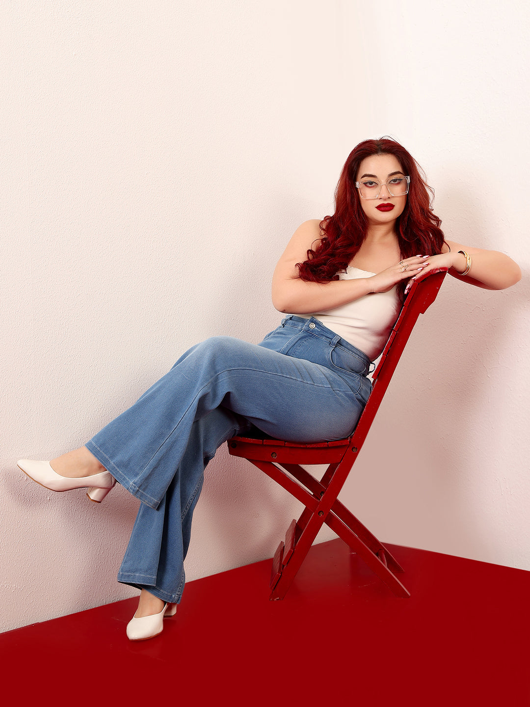 Mid-sized woman wearing a pair of Bootcut High-Rise Mid-Blue Denim Jeans which provides light tummy smoothening with the patented CHASEshapeTM Panel