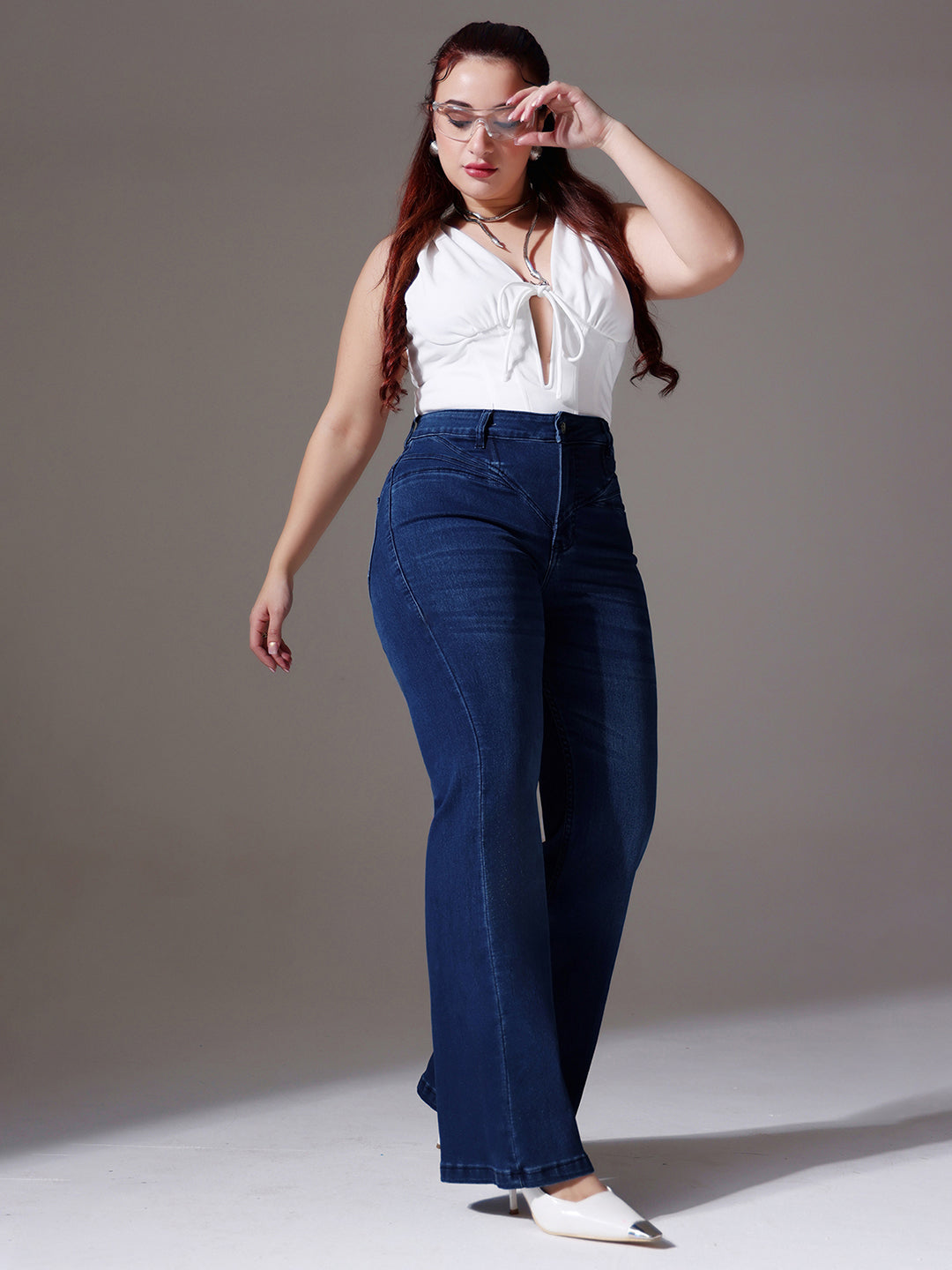 Mid-sized woman wearing a pair of Bootcut High-Rise Navy Blue Denim Jeans which provides light tummy smoothening with the patented CHASEshapeTM Panel