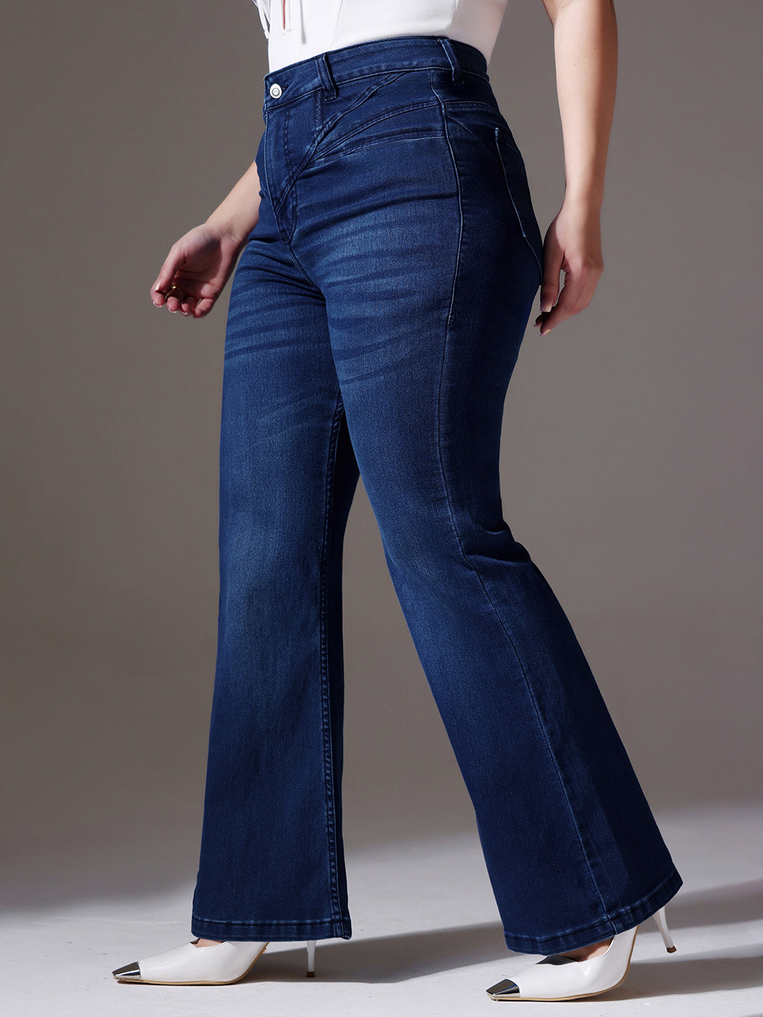 Mid-sized woman wearing a pair of Bootcut High-Rise Navy Blue Denim Jeans which provides light tummy smoothening with the patented CHASEshapeTM Panel