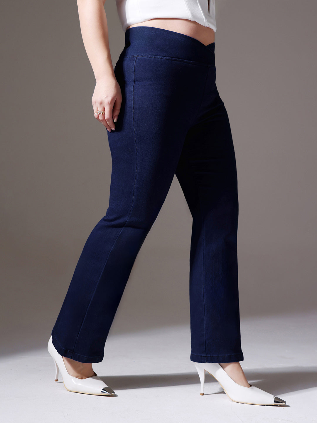 Mid-sized woman wearing a pair of Bootcut High-Rise Navy Blue Denim Jeans which provides light tummy smoothening with the patented CHASEshapeTM Panel