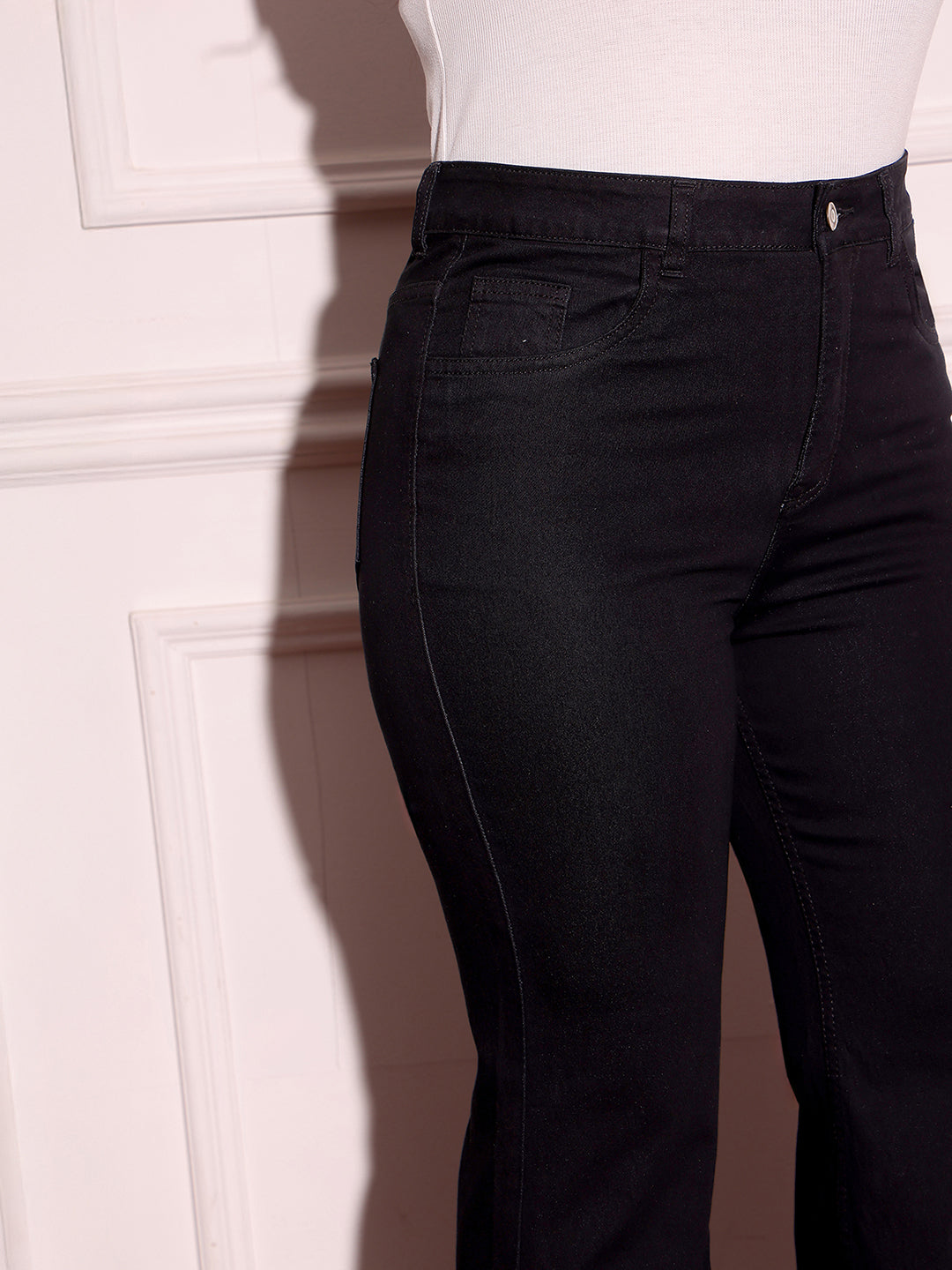 Mid-sized woman wearing a pair of Bootcut High-Rise Black Denim Jeans which provides light tummy smoothening with the patented CHASEshapeTM Panel