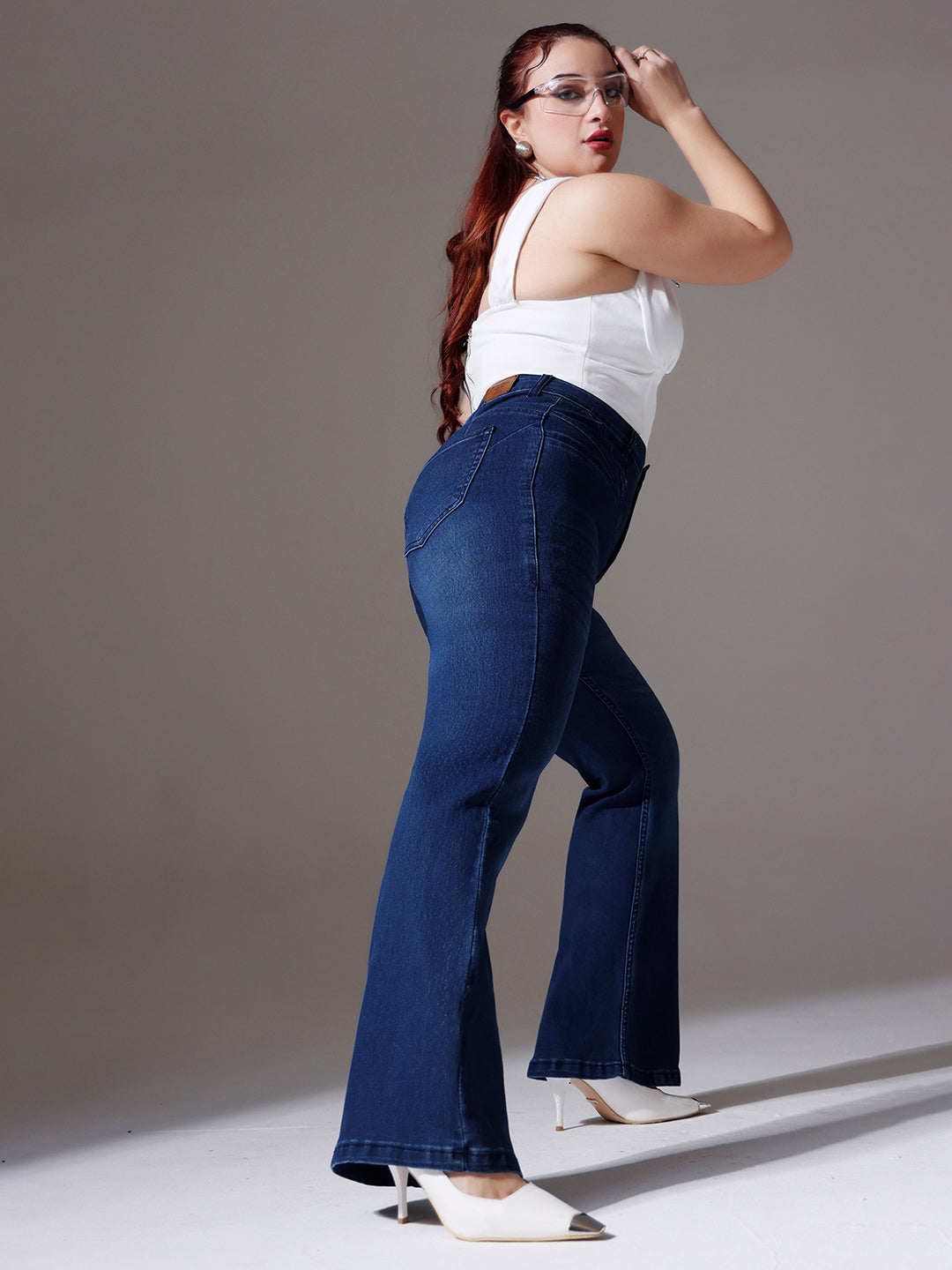 Mid-sized woman wearing a pair of Bootcut High-Rise Navy Blue Denim Jeans which provides light tummy smoothening with the patented CHASEshapeTM Panel