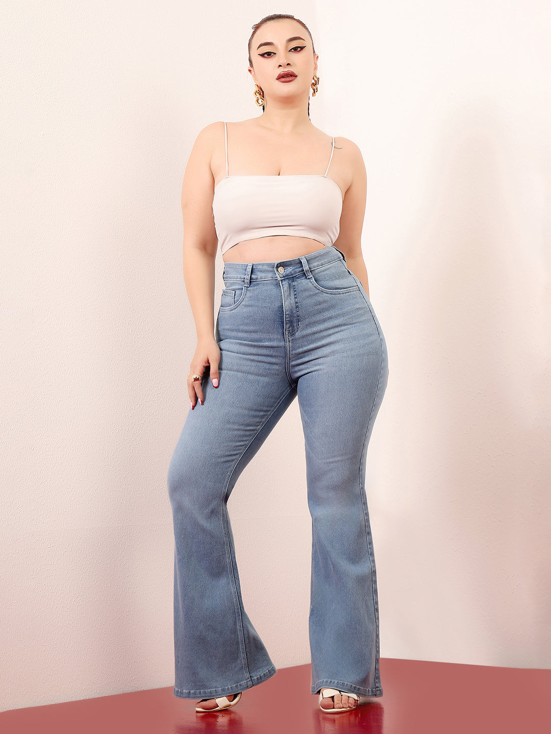 Mid-sized woman wearing a pair of Bootcut High-Rise Light Blue Denim Jeans which provides light tummy smoothening with the patented CHASEshapeTM Panel