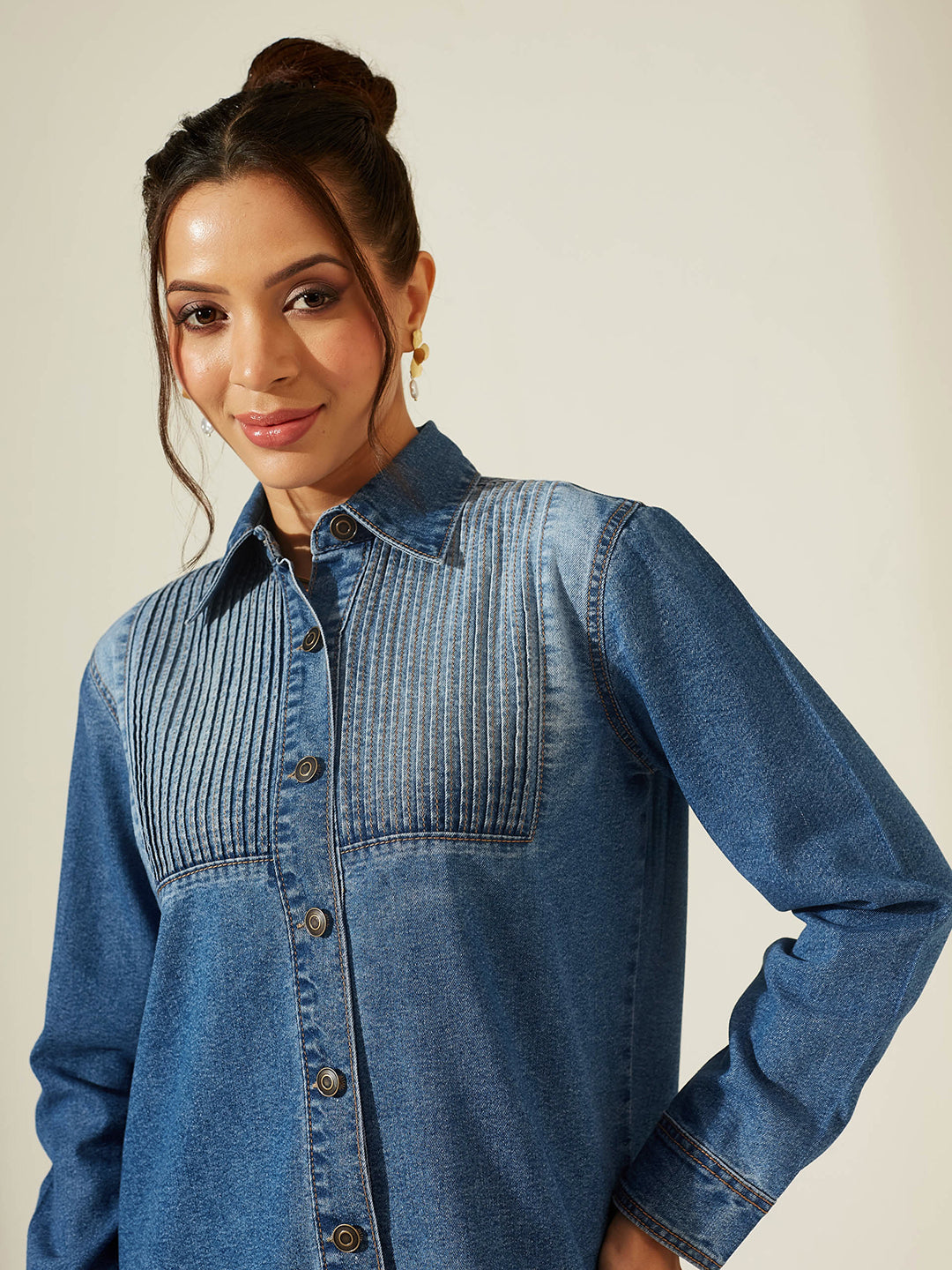 Woman wearing a blue denim shirt against a plain background