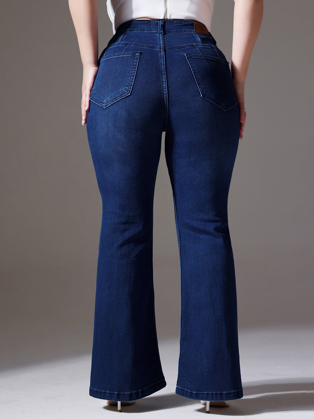 Mid-sized woman wearing a pair of Bootcut High-Rise Navy Blue Denim Jeans which provides light tummy smoothening with the patented CHASEshapeTM Panel