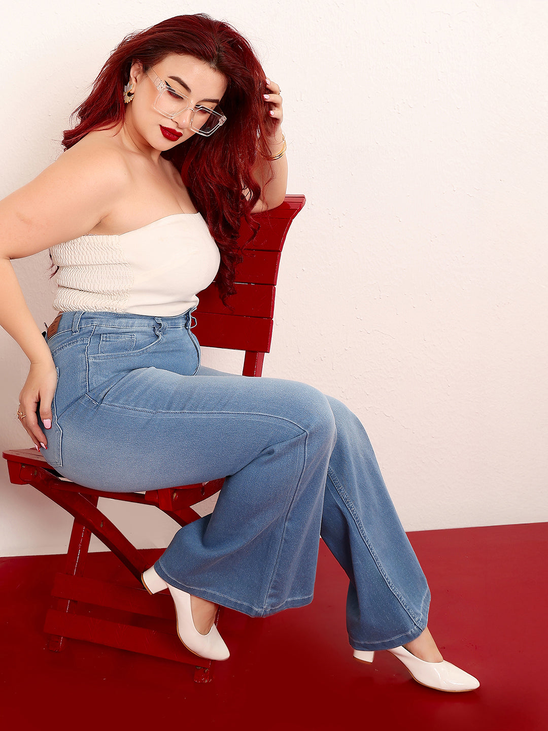 Mid-sized woman wearing a pair of Bootcut High-Rise Mid-Blue Denim Jeans which provides light tummy smoothening with the patented CHASEshapeTM Panel